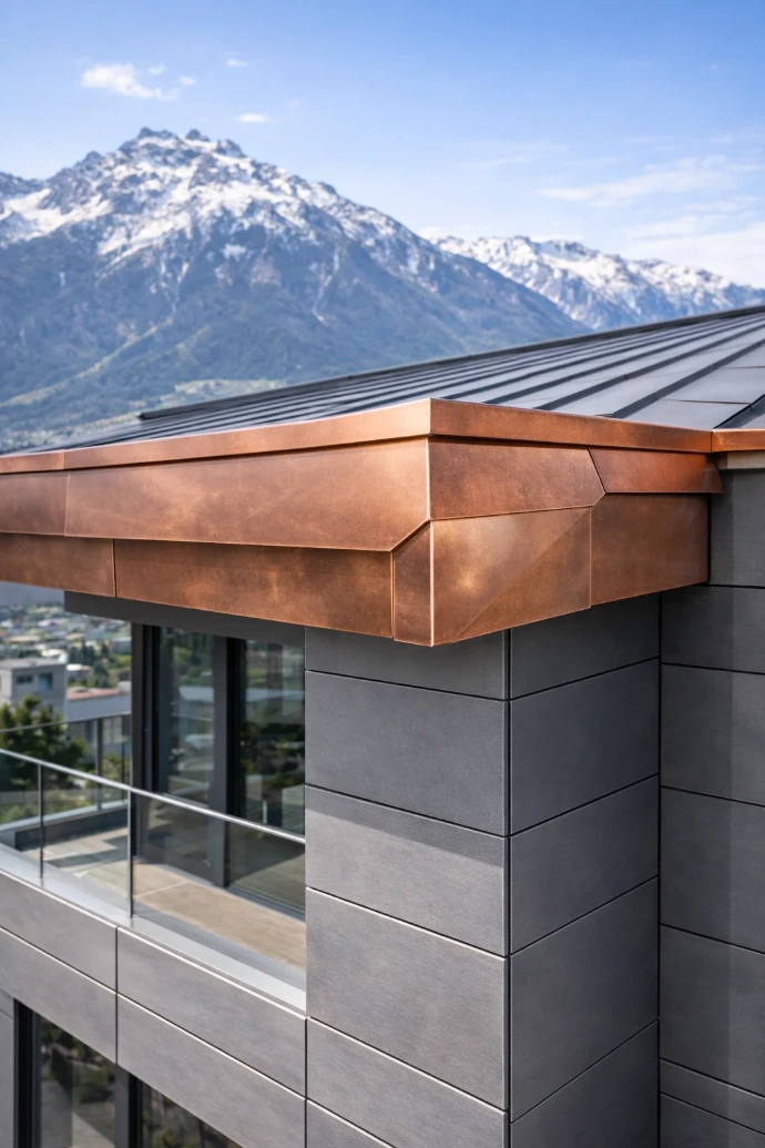 Maßgefertigte Kupfer-Blech-Sonderanfertigung an moderner Gebäudefassade in Innsbruck mit präziser Spenglerarbeit und klaren architektonischen Linien vor alpiner Kulisse