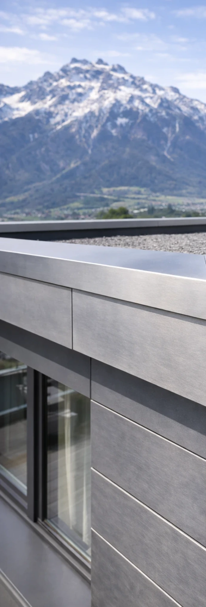 Professionell ausgeführter Flachdachabschluss mit Aluminium-Abdeckung an modernem Gebäude in Innsbruck, präzise Spenglerarbeit mit klarer Linienführung vor alpiner Kulisse